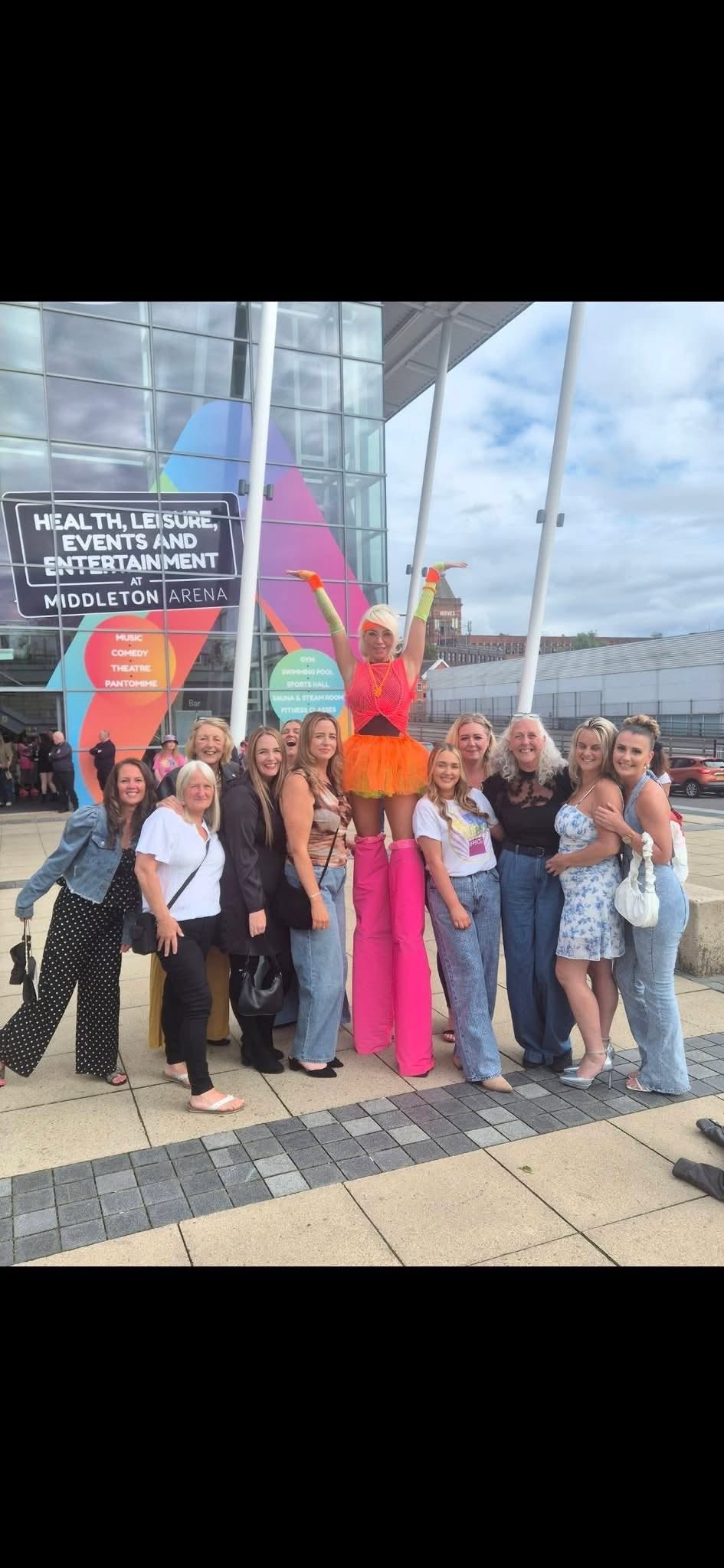 Concert attendees posing with a theatrical stilt walker outside Middleton Arena